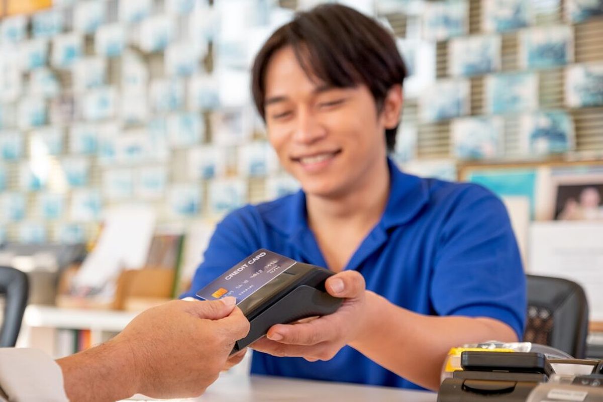 A smiling business owner takes a contactless credit card payment