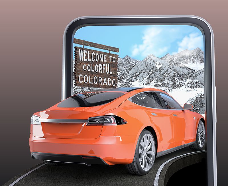 Orange car driving by Welcome to Colorado sign and a snowy mountain landscape